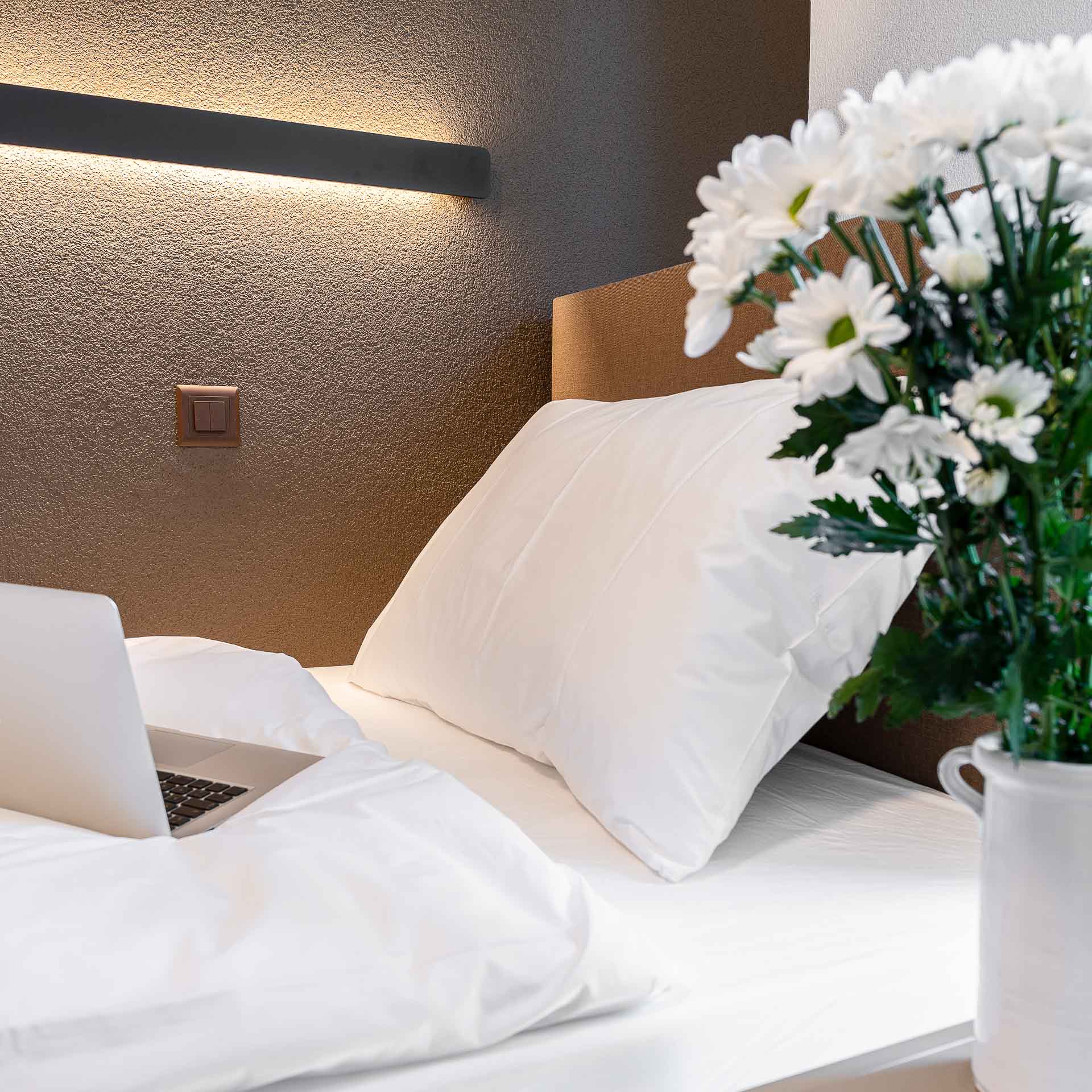 White bed with flowers on the nightstand 